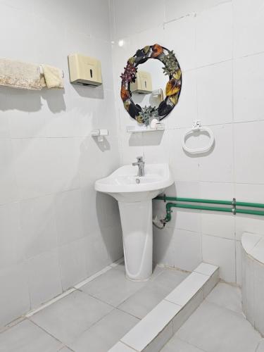 a white bathroom with a sink and a mirror at Farm N# 200 divan area in Al Khatim