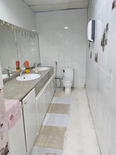 a white bathroom with a toilet and two sinks at Farm N# 200 divan area in Al Khatim