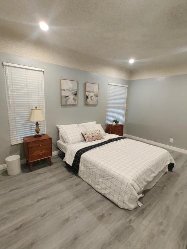 a bedroom with a large bed and two windows at sofi intuit cozy home free parking queen beds in Inglewood