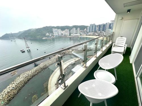 a balcony with tables and chairs and a view of the water at THE DECEMBER STAY Busan Songdo Ocean Terrace in Busan