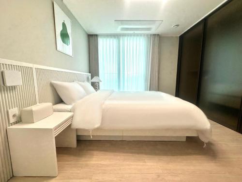 a bedroom with a large white bed and a window at THE DECEMBER STAY Busan Songdo Ocean Terrace in Busan