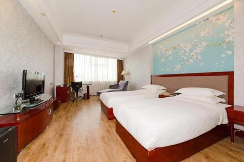 a hotel room with two beds and a flat screen tv at Junyu Grand Hotel Qinhuangdao in Qinhuangdao