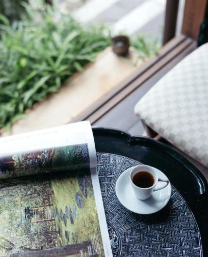 a cup of coffee sitting on a table with a book at Rakumankan in Kyoto