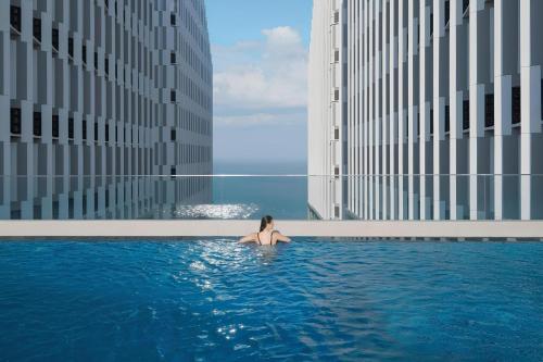 una mujer sentada en una piscina en un edificio en Nguyên Vũ Apec Mũi Né Mandala, en Ấp Thiẹn Ái