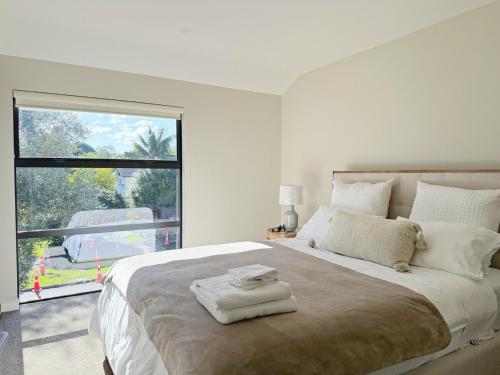 a bedroom with a large bed with a large window at Brand-New Luxury 5 bedroom house in Epsom in Auckland