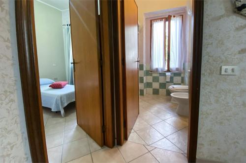 a bathroom with a toilet and a room with a bed at Civico 21 in Càbras