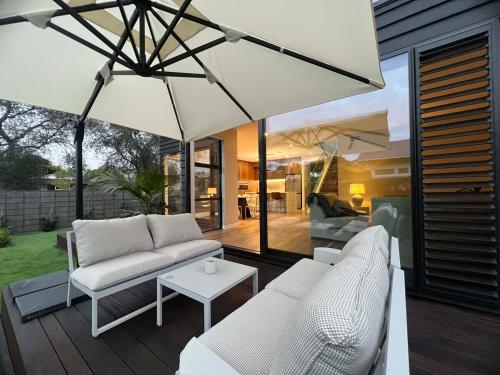 a patio with white furniture and a large umbrella at Brand-New Luxury 5 bedroom house in Epsom in Auckland