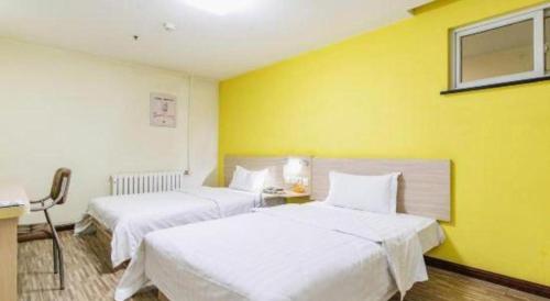 two beds in a hotel room with yellow walls at 7 Days Inn Tianjin Binhai New District Yujiabao Metro Station in Binhai