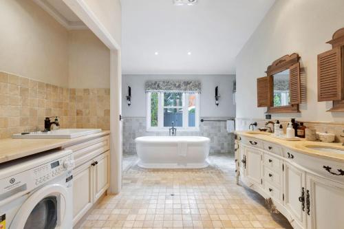 ein Badezimmer mit einer Badewanne, einem Waschbecken und einer Waschmaschine in der Unterkunft Collins Cottage - Luxury Accommodation in Bright