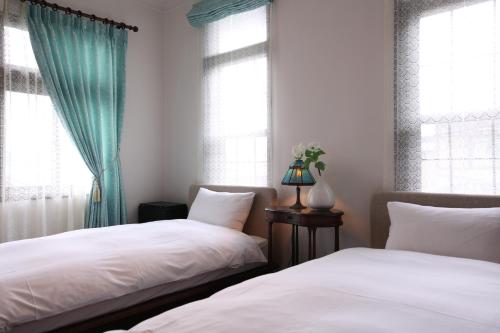 two beds in a room with two windows at Rakumankan in Kyoto