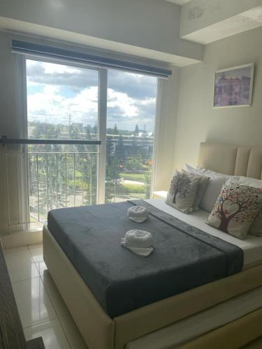 a bedroom with a large bed with a large window at Wind and Sea at Wind Residences in Tagaytay