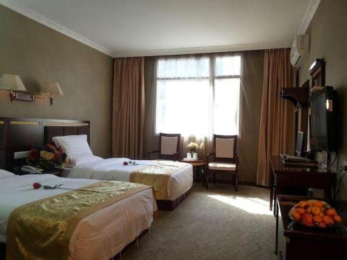 a hotel room with two beds and a television at Guo Bin Hotel in Danjiangkou