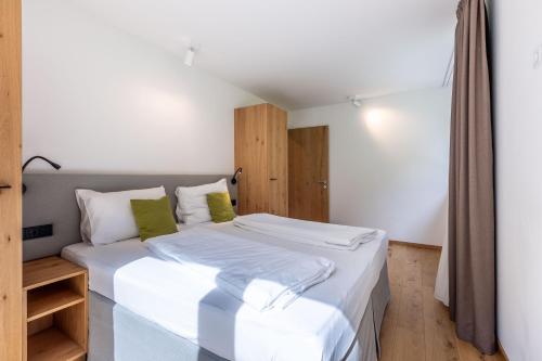 a bedroom with a bed with white sheets and green pillows at keyone homes Zwieselstein in Sölden
