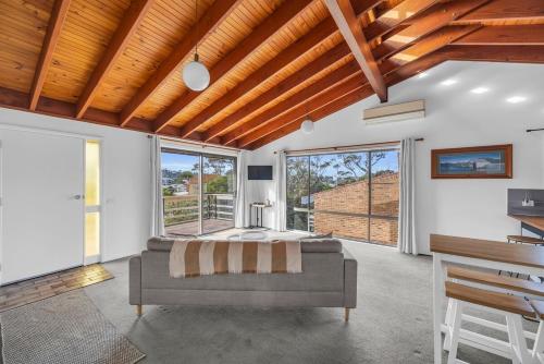 a bedroom with a bed and large windows at Retreat on Reid Street in Merimbula