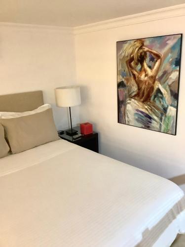 a bedroom with a white bed and a painting on the wall at Dar Lalzohra in Rabat