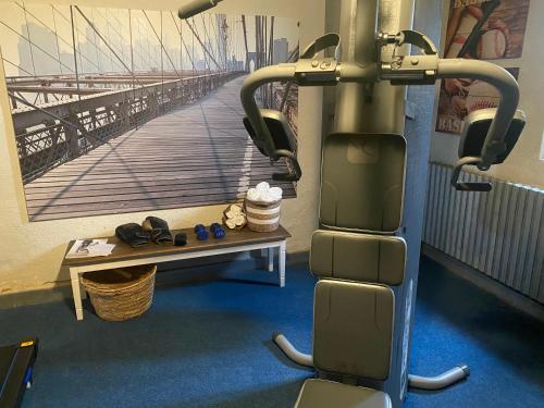 une pièce avec une salle de sport avec un banc et une image d'un pont dans l'établissement GITE de LAS TREILLES, à Puylaroque