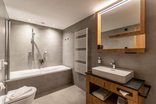 a bathroom with a sink and a tub and a toilet at keyone homes Zwieselstein in Sölden