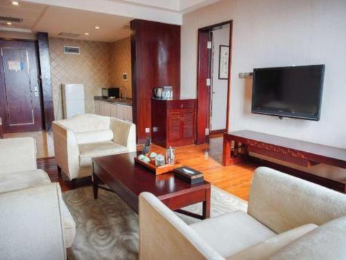 a living room with a couch and a tv at Kunming Wenhui Hotel in Kunming