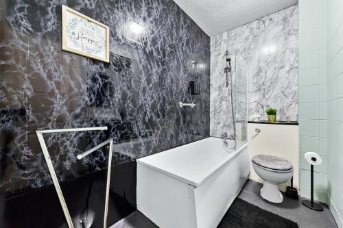 a black and white bathroom with a toilet and a tub at Bright modern Flat near tower bridge in London