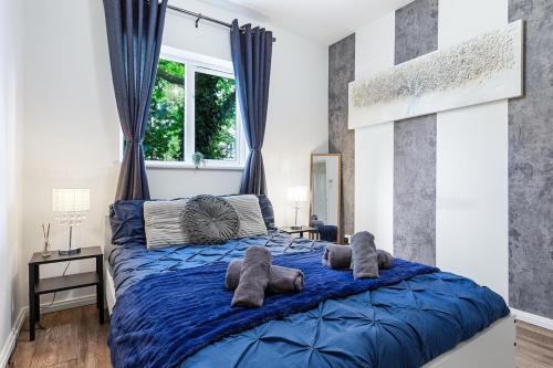 a bedroom with a blue bed with two stuffed animals on it at Bright modern Flat near tower bridge in London