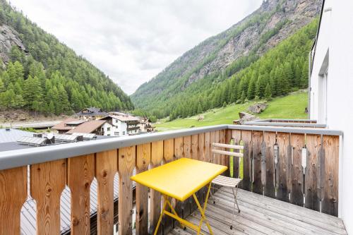 a yellow table on a balcony with a view of mountains at keyone homes Zwieselstein in Sölden
