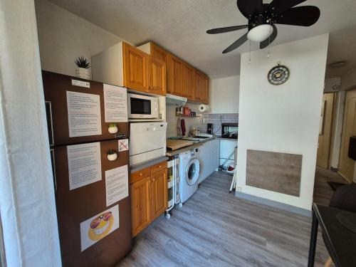 Il comprend une cuisine avec des placards en bois et un ventilateur de plafond. dans l'établissement Joli T2 place parking 4 pers, à Cavalaire-sur-Mer