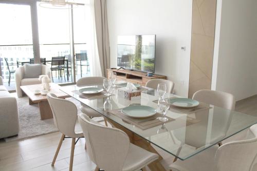 a dining room with a glass table and chairs at Palace Residences luxurious 2 bedroom with breathtaking views in Dubai