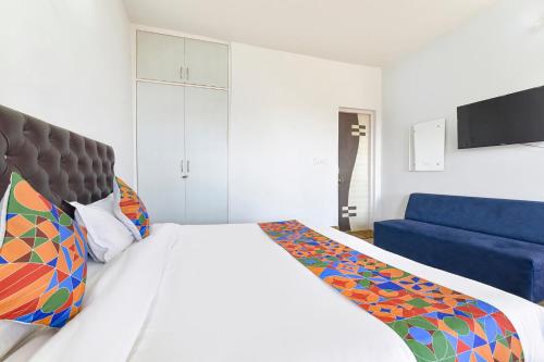ein Schlafzimmer mit einem Bett und einer blauen Couch in der Unterkunft FabHotel Green Acres in Dhanaulti