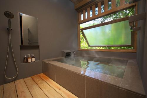 a large bathroom with a tub and a window at Sekizenkan Kashotei Sanso in Nakanojo