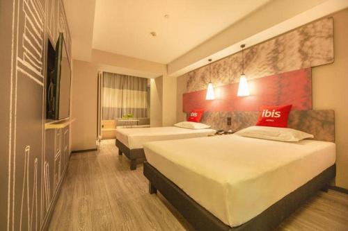 a hotel room with two beds and a tv at ibis Shenyang north station in Shenyang