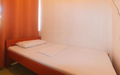 a small bed in a room with an orange curtain at Stay Malate Hostel by RedDoorz in Manila