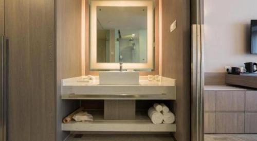 a bathroom with a sink and a mirror and towels at Jinjiang Metropolo Shanghai Xujiahui Nanhuating Hotel in Shanghai