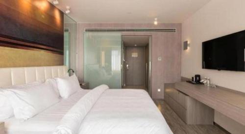 a bedroom with a large white bed and a flat screen tv at Jinjiang Metropolo Shanghai Xujiahui Nanhuating Hotel in Shanghai