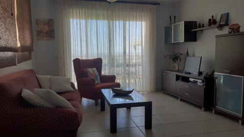 Una sala de estar con un sofá, una mesa y un televisor. en Superbe appartement, en Peñíscola