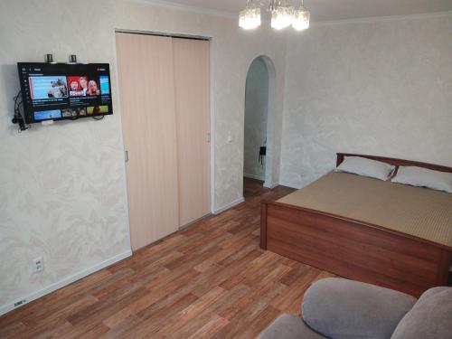 a bedroom with a bed and a tv on the wall at Апартаменты в центре города со смарт тв и Wi-Fi in Karagandy