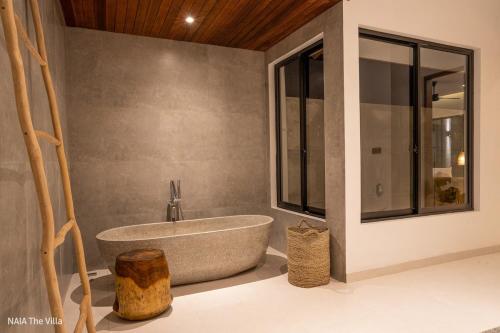 a bathroom with a tub and a large window at NAIA The Villa - Modern Tropical Retreat in Canggu