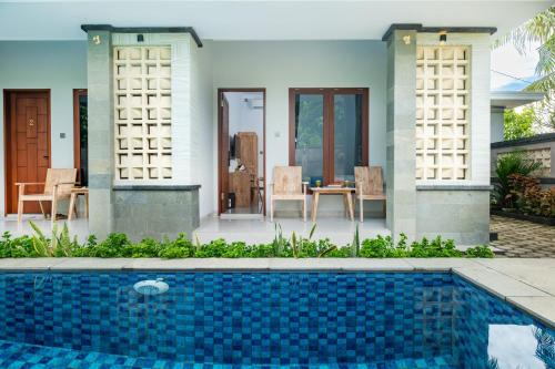 a villa with a swimming pool in front of a house at Kemala Living Sanur in Sanur
