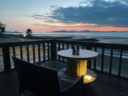 a table with two bottles of beer sitting on a balcony overlooking the beach at HOJO Brewing & Stays in Hōjō