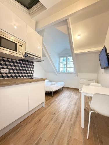 une cuisine avec des armoires blanches, une table et un canapé dans l'établissement Cocoon in the 16th Eiffel Tower and Roland Garros, à Paris