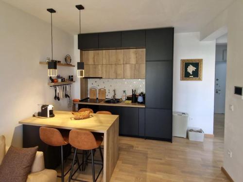 eine Küche mit schwarzen Schränken und einem Holztisch in der Unterkunft Apartment ENJOY in Bar