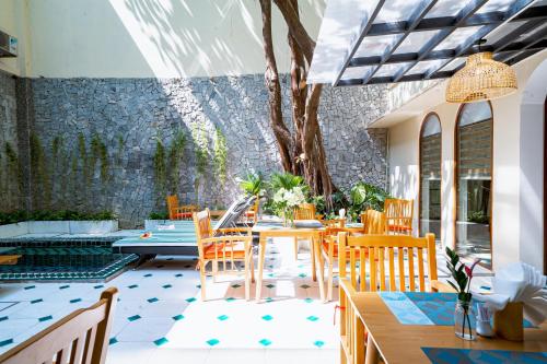 a patio with a table and chairs and a stone wall at Sujet Residence Da Nang by Haviland in Da Nang