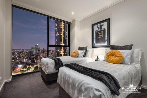 two beds in a room with a large window at Platinum Luxury Stays The Grande Large 4 BRM 3 Bath Apt in Melbourne
