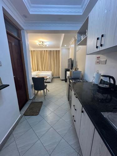 a kitchen with a counter and a room with a bed at Pamoja stays - Modern studio near transit with balcony and workspace in Rungiri
