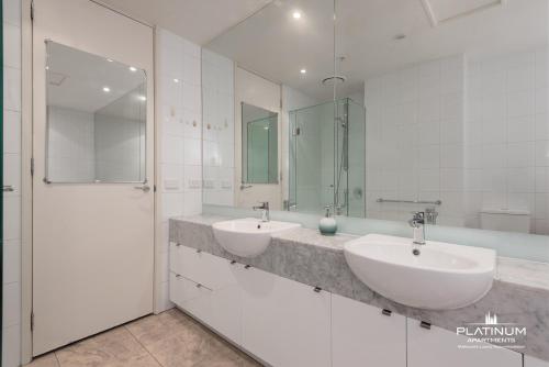a white bathroom with two sinks and a shower at Platinum Luxury Stays The Grande Large 4 BRM 3 Bath Apt in Melbourne