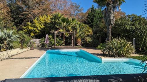 une piscine bleue dans une cour arborée dans l'établissement Maison Côté Bordeaux Saint-Émilion Piscine Privée 3 Chambres, à Sadirac