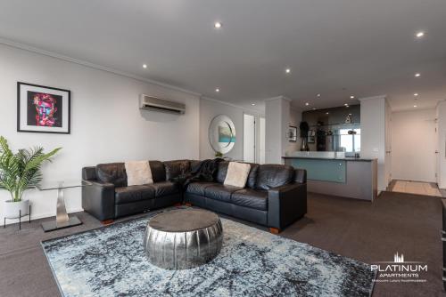 a living room with a leather couch and a table at Platinum Luxury Stays The Grande Large 4 BRM 3 Bath Apt in Melbourne