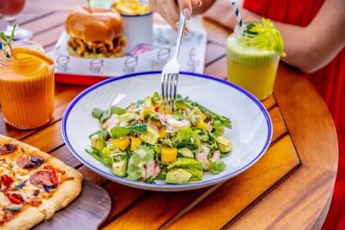 a table with a plate of salad and a pizza at Rove Al Marjan Island in Ras al Khaimah