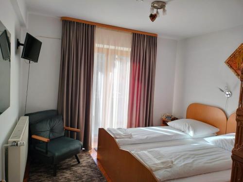 una stanza d'albergo con due letti e una sedia di Pensiunea Irina a Vama