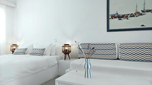 a white bedroom with two beds and a table at Narges Hotel in Aliki