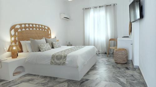 a white bedroom with a white bed and a television at Narges Hotel in Aliki